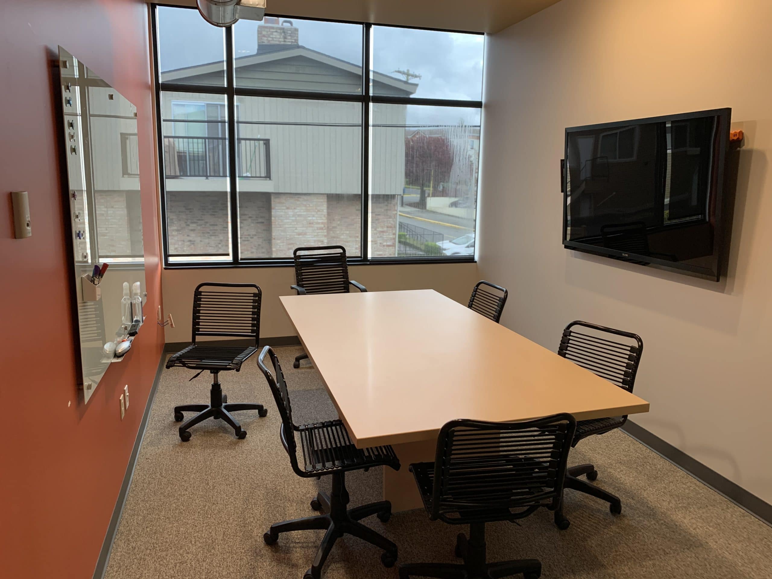 conference room for rent with chairs, desk, whiteboard, and tv